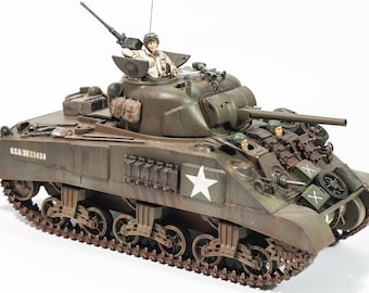 May include: A green military tank model with a white star on the side. The tank has a crew of four soldiers, including a driver, gunner, and two loaders. The tank is labeled "U.S.A. 3033434".