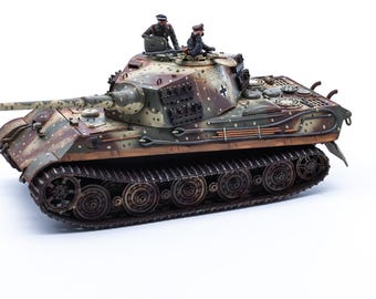 May include: A scale model of a German King Tiger tank featuring a camouflage paint scheme of green, brown, and tan spots. The tank has a long main gun, dark tracks, and two miniature figures positioned in the open turret hatch with the number 551.