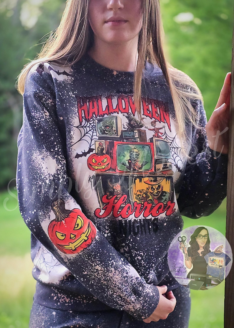 May include: A black sweatshirt with a white splatter design. The sweatshirt has a graphic print of a pumpkin and the text "Halloween Horror Nights".