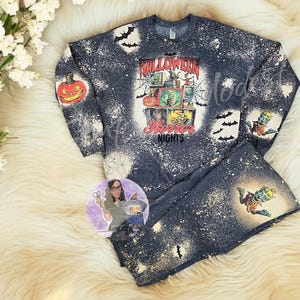 May include: A black and white bleached long-sleeved shirt with a graphic print of a vintage television set with a Halloween theme. The shirt says "Halloween Horror Nights".