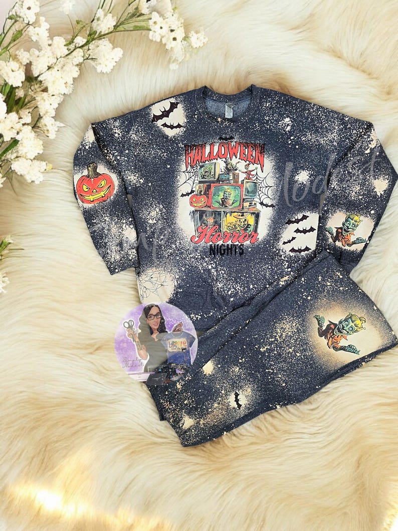 May include: A black and white bleached long-sleeved shirt with a graphic print of a vintage television set with a Halloween theme. The shirt says "Halloween Horror Nights".