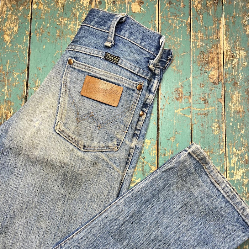 Pode incluir: Jeans Wrangler de ganga azul clara com lavagem desbotada. Os jeans apresentam um patch de couro castanho com o logotipo Wrangler no bolso traseiro. Os jeans t&ecirc;m um design cl&aacute;ssico de cinco bolsos e fecho de bot&atilde;o e z&iacute;per.
