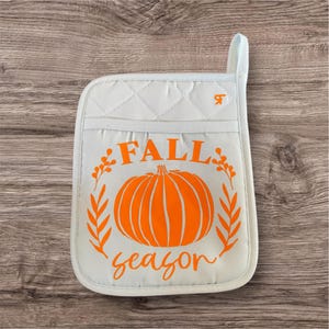 May include: White quilted oven mitt with an orange pumpkin and the text "FALL season" in a wreath of leaves.