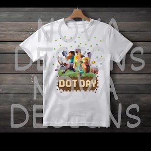 May include: White t-shirt featuring a pixelated graphic of characters from a video game, with the text "DOT DAY" in a pixelated font. The design includes green and brown elements.