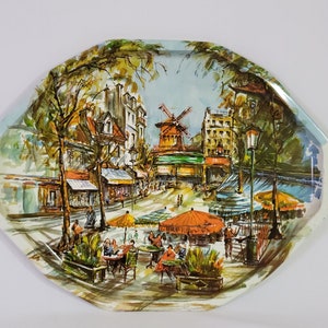 以下が含まれることがあります： 風車、建物、木々、屋外カフェに座っている人々を描いた、カラフルな絵が描かれたヴィンテージの金属製のトレイ。