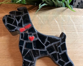 May include: Black mosaic dog figurine with red heart accents. The dog is standing on a wooden surface.