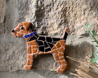 May include: A mosaic tile artwork of a brown and black dog with a blue collar. The dog is standing on a stone wall.