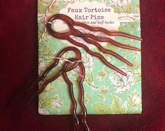 May include: Three brown faux tortoise hair pins in a floral patterned package. The package says "Faux Tortoise Hair Pins three and half inches".
