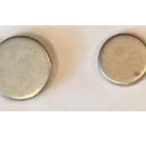 Puede incluir: Dos discos de metal de color plateado de diferentes tamaños. El disco más grande está a la izquierda y el disco más pequeño está a la derecha.