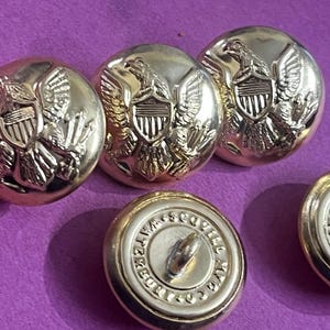 Op de afbeelding: Vijf gouden knopen met een adelaar- en schildontwerp. Eén knop heeft de tekst "FREEDOM SCOUTS" rond de rand.