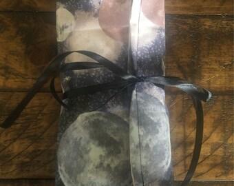 May include: A black fabric pouch with a moon and stars print. The pouch is tied with a black ribbon.