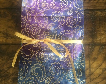 May include: A purple and blue fabric pouch with a gold paisley pattern. The pouch is tied with a gold ribbon.