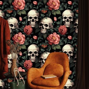 May include: A black and white wallpaper with a repeating pattern of skulls and pink flowers. The wallpaper is in a room with a brown chair and a green bag.