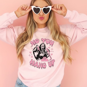 May include: Pink sweatshirt with a graphic of a ghost holding a knife and a phone. The text "No You Hang Up" is written in pink dripping letters.