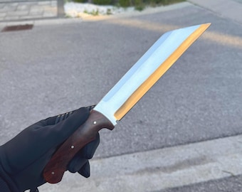May include: A fixed-blade knife featuring a long, straight-edged silver metal blade with a distinct gold-toned bevel and a dark brown wooden handle secured with three small silver rivets, held in a black gloved hand against an outdoor background.