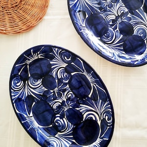 May include: Two oval ceramic platters with a dark blue floral design on a white background. The platters are decorated with stylized flowers and swirling patterns. A woven basket is in the upper left corner.