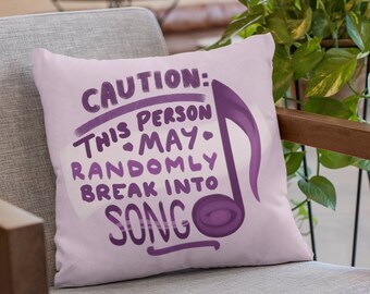 Könnte beinhalten: Ein rosa Kissen mit einer violetten Musiknote und dem Text "ACHTUNG: DIESE PERSON KANN PLÖTZLICH MIT DEM SINGEN BEGINNEN".