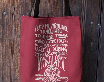 Könnte beinhalten: Rote Einkaufstasche mit schwarzen Henkeln und weißem Text, der lautet "Keep me around. I know how to make things ~and therefore~ will be very very useful during the zombie apocalypse."  Unter dem Text ist eine weiße Wollknäuel mit Stricknadeln abgebildet.