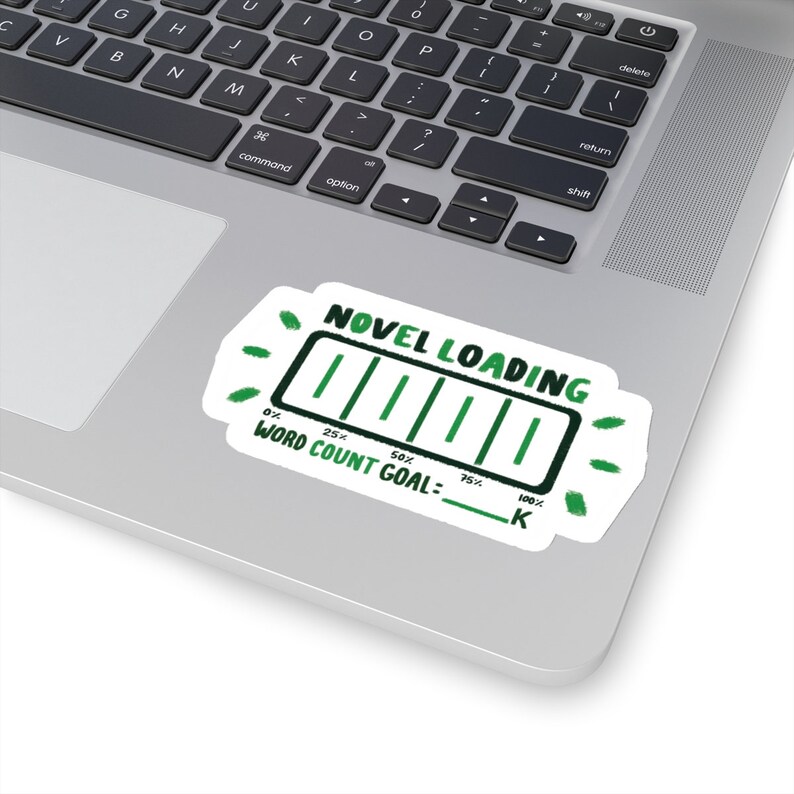 Peut inclure: Un autocollant blanc avec une barre de progression verte qui indique "NOVEL LOADING" et "WORD COUNT GOAL: ____ K". La barre de progression est remplie de vert et indique 75% de compl&eacute;tion.
