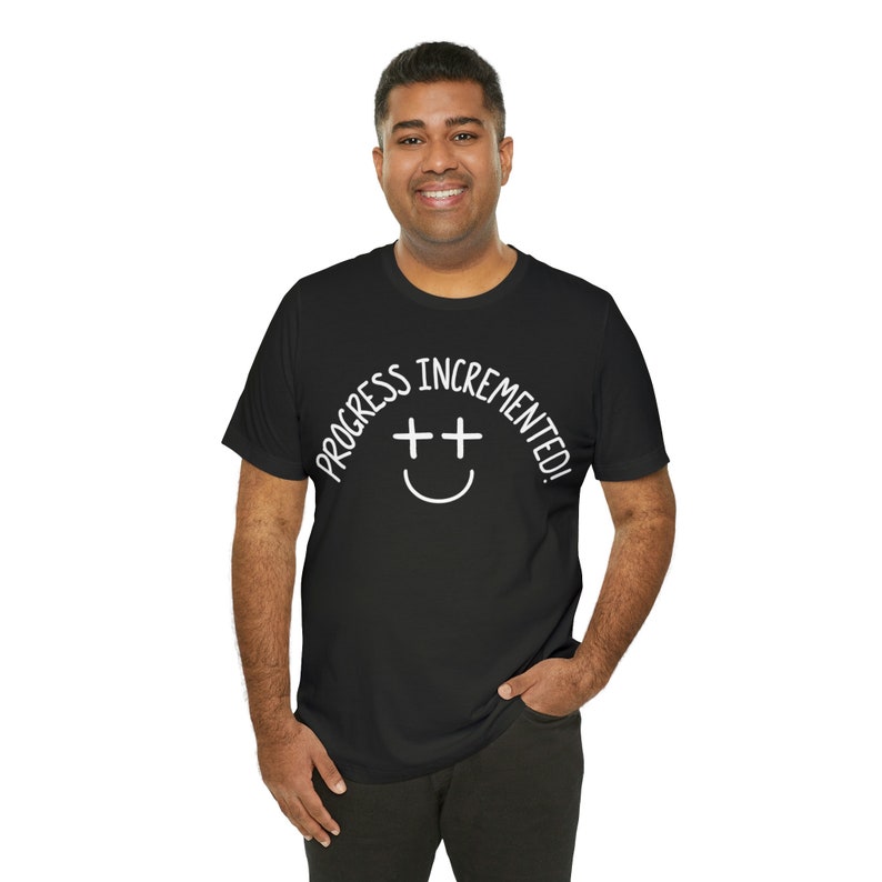 May include: A black t-shirt with white text that reads "Progress incremented!" with a smiley face graphic.