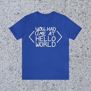 May include: A royal blue t-shirt with white text that reads "you had me at <hello world>"