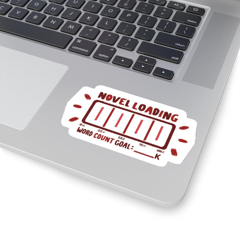 Peut inclure: Un autocollant blanc avec une barre de progression rouge qui indique "NOVEL LOADING" et "WORD COUNT GOAL: ____ K". La barre de progression est remplie de rouge et indique 75% de compl&eacute;tion.