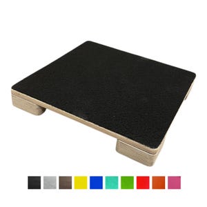 May include: A wooden footrest with a black, textured top surface. The footrest has a rectangular shape and is supported by four rounded wooden feet. The base is made of layered wood. A color palette of available colours is shown below the footrest.