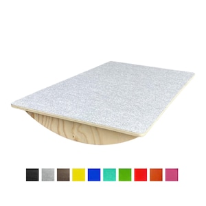 Op de afbeelding: Een grijs balansbord met een textuuroppervlak, geplaatst op een gebogen houten basis. Het bord is rechthoekig en heeft een lichtgrijs gespikkeld ontwerp. Een rij kleurstalen staat onderaan.