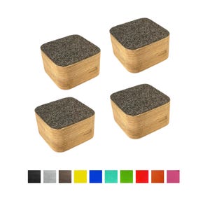 Op de afbeelding: Vier vierkante onderzetters met een lichtbruine, gelaagde houten basis en een donkergrijze, getextureerde bovenkant. De onderzetters zijn gerangschikt op een witte achtergrond. Een kleurenpalet van zwart, grijs, bruin, geel, blauw, groen, rood, oranje en roze wordt hieronder getoond.