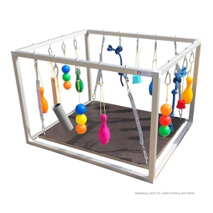 Könnte beinhalten: Ein weißes Metallspielgerüst mit verschiedenen hängenden Spielzeugen. Die Spielzeuge umfassen bunte Kugeln, Kegelformen und Seilknoten. Die Struktur hat eine dunkelbraune Basis und ist für interaktives Spielen konzipiert.