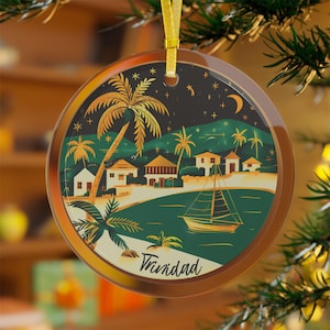 May include: Round Christmas ornament featuring a tropical island scene with palm trees, houses, and a sailboat. The ornament has a gold rim and a gold ribbon for hanging. The word "Trinidad" is written on the bottom.