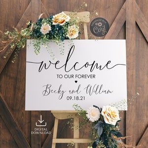 May include: White wedding welcome sign with black calligraphy text that reads "Welcome to our forever Becky and William 09.18.21". The sign is leaning against a wooden easel and surrounded by white and yellow flowers.