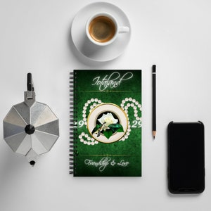May include: A green spiral bound journal with the words "Totaland Friendship & Love" on the cover. The cover features a white rose and a hummingbird with a pearl necklace around the design.