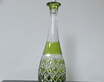 May include: A tall glass decanter featuring a clear and lime green color scheme. The base has a diamond-cut pattern, transitioning to a smooth green band and a long, slender neck. It includes a matching stopper with a diamond-cut design.
