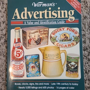 May include: A book titled "Warman's Advertising: A Value and Identification Guide." The cover features vintage advertisements for Pepsi-Cola, Rocky Ford Cigars, and other products. The book is an encyclopedia of antiques and collectibles, with over 5,000 listings and 600 photos.