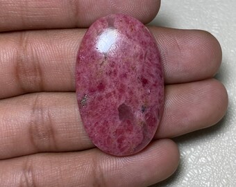 May include: A pink and white oval cabochon gemstone with a speckled pattern. The stone is set in a silver bezel.