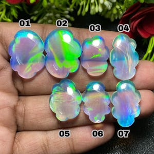 May include: Seven iridescent opal gemstones with a flower-like shape are displayed. Each stone has a unique play of color, including blues, greens, and pinks. The gemstones are numbered 01 through 07.