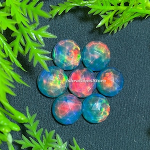 May include: Seven iridescent opal cabochons in a variety of colors, including blue, green, pink, and orange. The cabochons are faceted and have a smooth, polished finish.