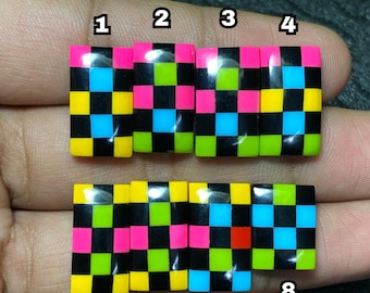 May include: Eight rectangular, colorful beads with a checkerboard pattern. The beads feature a repeating pattern of black, pink, yellow, green, blue, and red squares. The beads are numbered 1 through 8.
