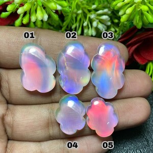 May include: Five iridescent opal gemstones in a flower-like shape. The opals display a range of colors, including pink, blue, and orange, with a translucent quality. Each stone is numbered for identification.