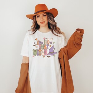 May include: White t-shirt with a colorful graphic that says "I'm 100% That Witch" with a witch's hat and stars.