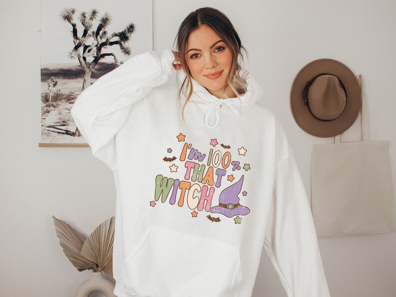 May include: White hooded sweatshirt with a colorful graphic that says "I'm 100% That Witch" with a purple witch hat and stars.