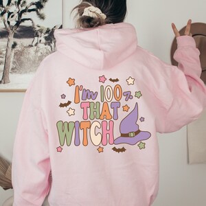 May include: Pink hoodie with a graphic print that says "I'm 100% That Witch" with a purple witch hat and stars.