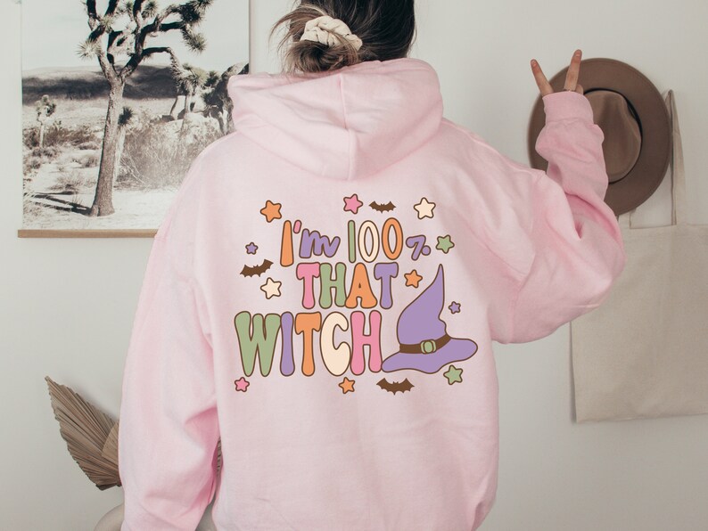 May include: Pink hoodie with a graphic print that says "I'm 100% That Witch" with a purple witch hat and stars.