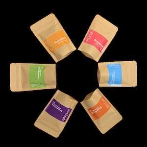 Könnte beinhalten: Sechs kleine braune Papiertüten mit verschiedenen farbigen Etiketten. Jede Tüte trägt den Text "get fresh" und einen anderen Frucht- oder Geschmacksnamen. Die Geschmacksrichtungen sind: Kürbis, Grapefruit, Zitronengras, Pfefferminze, Brombeere und Sternfrucht.