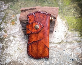 May include: A brown leather wallet with a stitched design and a brass button closure. The wallet has a distressed look and is made of high-quality leather.