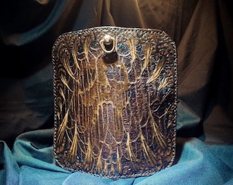 Könnte beinhalten: Eine handgefertigte braune Ledergeldbörse mit geprägtem Design. Die Geldbörse hat ein detailliertes Muster und einen Metallringverschluss. Das Leder hat ein abgenutztes, Vintage-Aussehen mit Farb- und Texturvariationen.