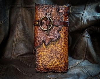 Op de afbeelding: Een bruine leren portemonnee met een sleutelgatontwerp en een metalen sleutelbedel. De portemonnee heeft een verweerde look en is gemaakt van hoogwaardig leer.