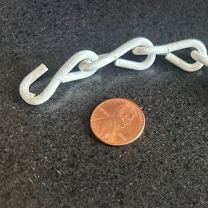 May include: A light gray metal chain with a hook on each end. A copper penny is next to the chain for size comparison. The chain links are in a figure-eight shape.