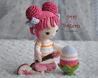 May include: Crochet pattern for a pink and white doll holding a pastel colored Easter egg. The pattern is written in English and is available as a PDF download.